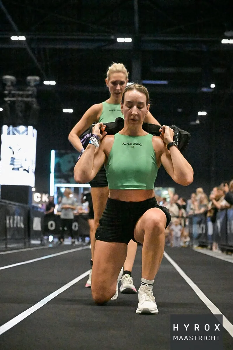 Mirthe Geurts en Loes van Schijndel bij de sandbag lunges in de doubles van HYROX Maastricht 2026